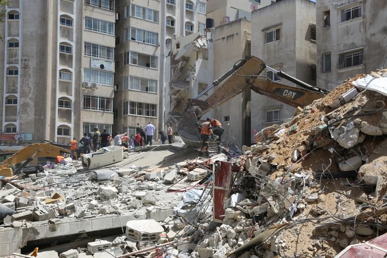 Heavy machinery demolishing urban buildings with workers clearing debris.